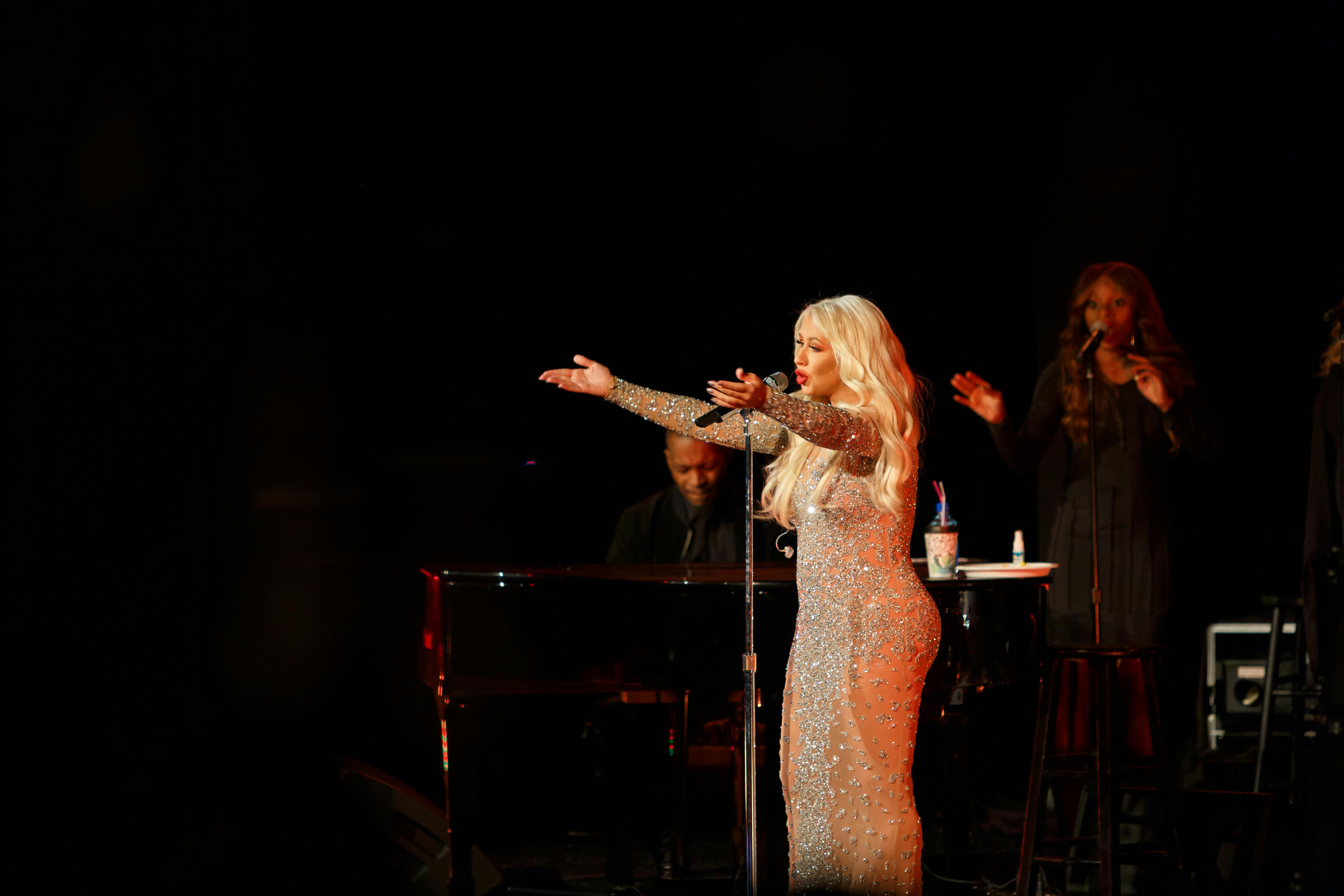 Christina Aguilera sings on stage with her arms outreached