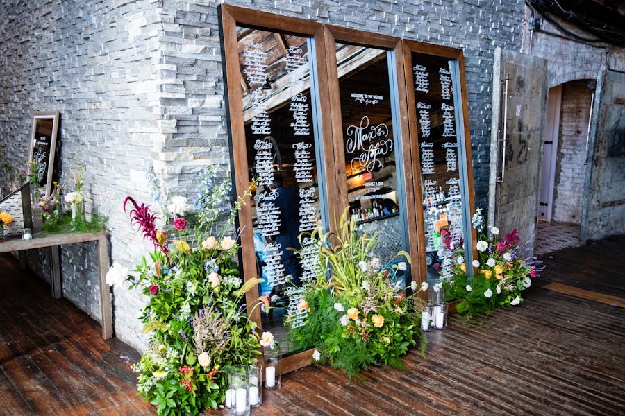 a mirror holds seating arrangements against a painted brick wall. Leafy floral arrangements sit at the bottom.