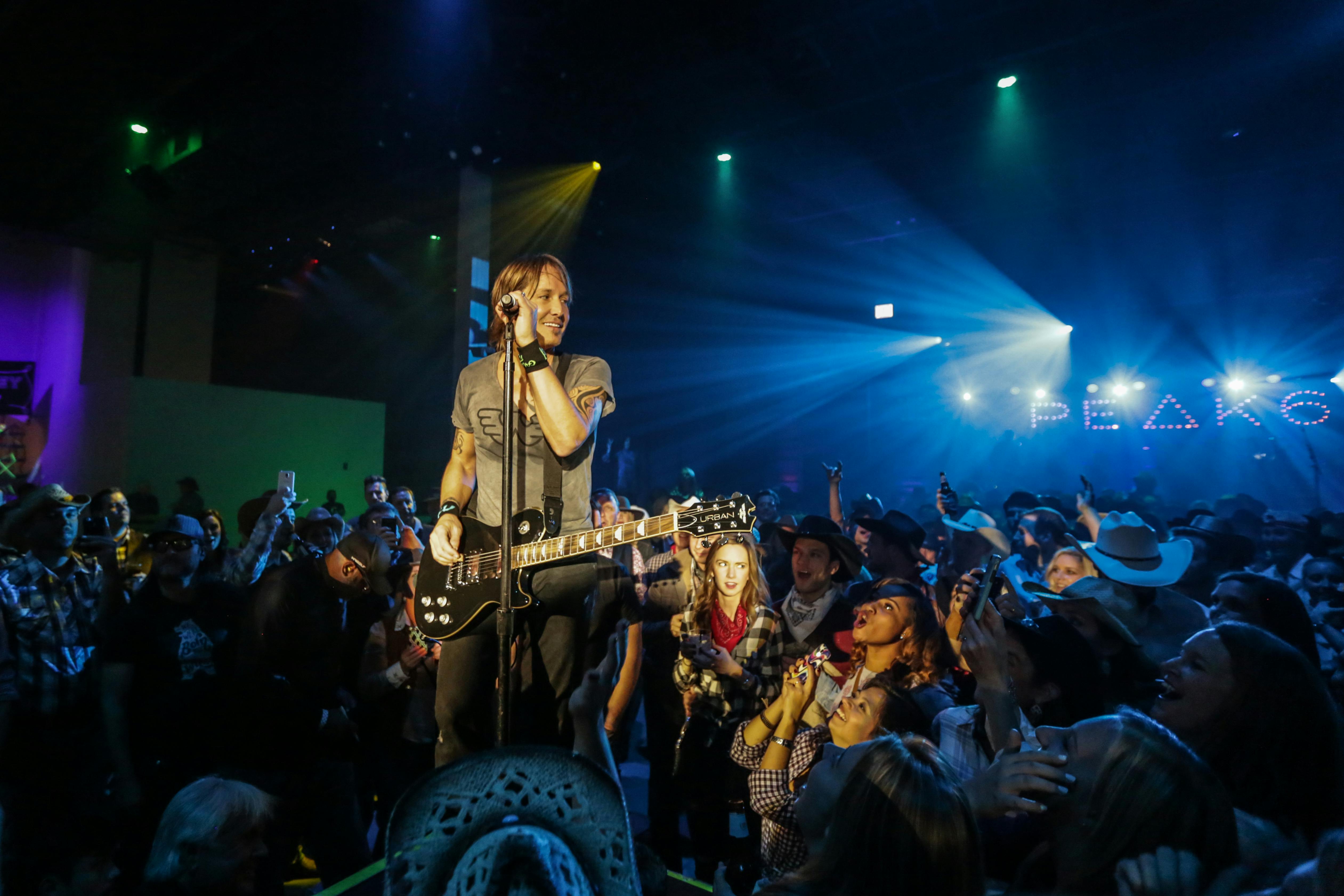 Keith Urban on stage with people around him. 