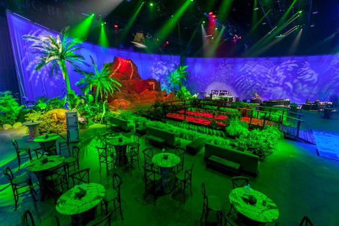 Jurassic Park themed party with rocks and leafy installations and greenn lighting | PartySlate