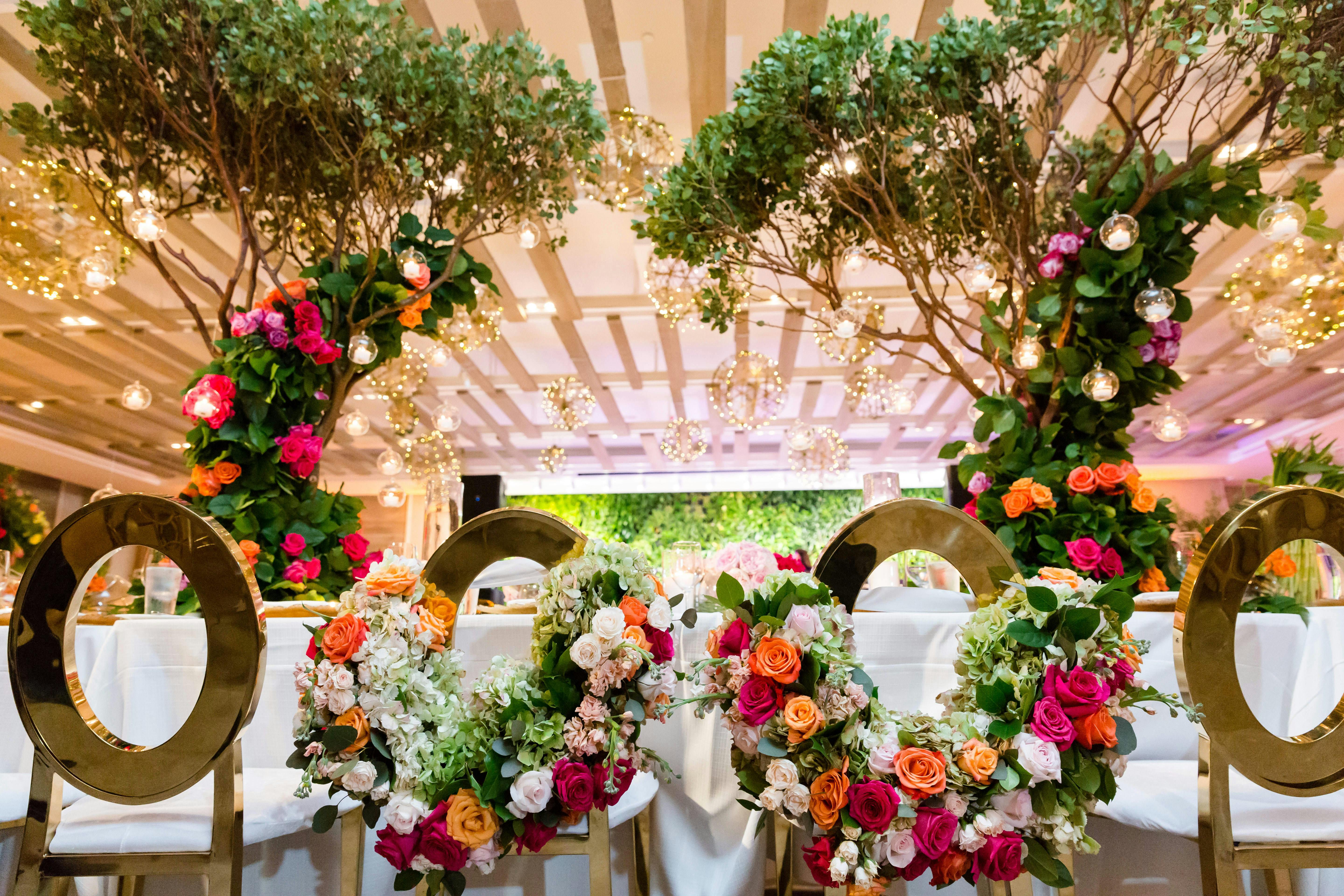 A symmetrical bride and groom table with colorful florals and fairy lights. 