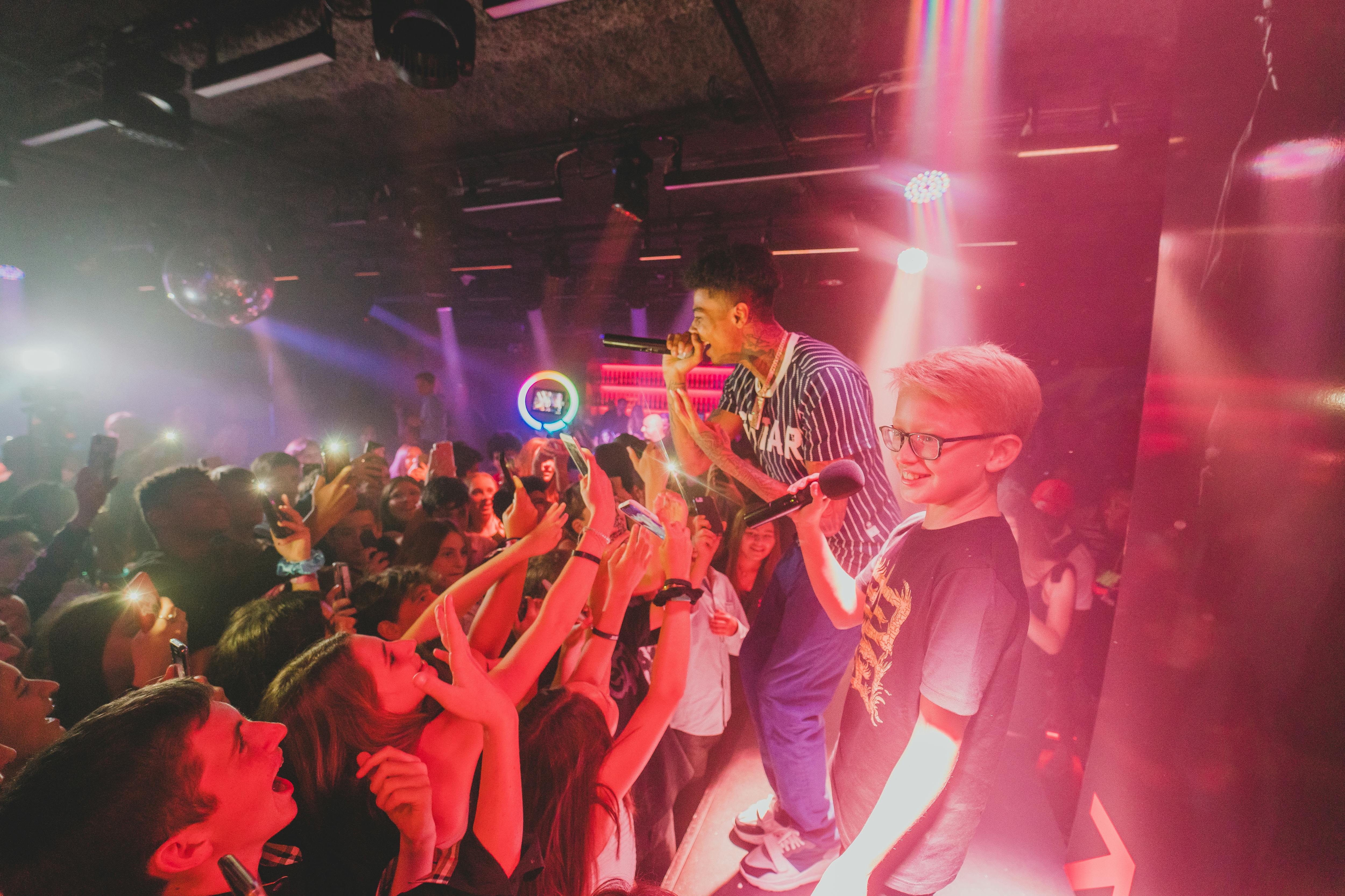 a tapper and the bar mitzvah boy are on stage with the audience at their feet. Red lights are around them.