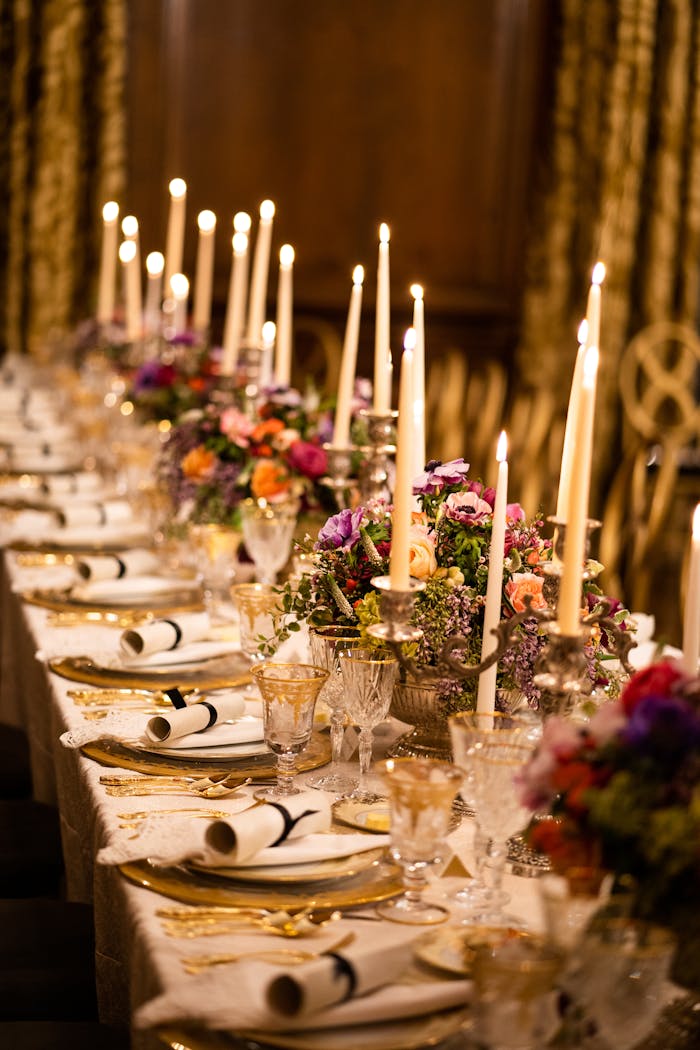 Elegant dinner table with golden plates and cutlery and candles | PartySlate