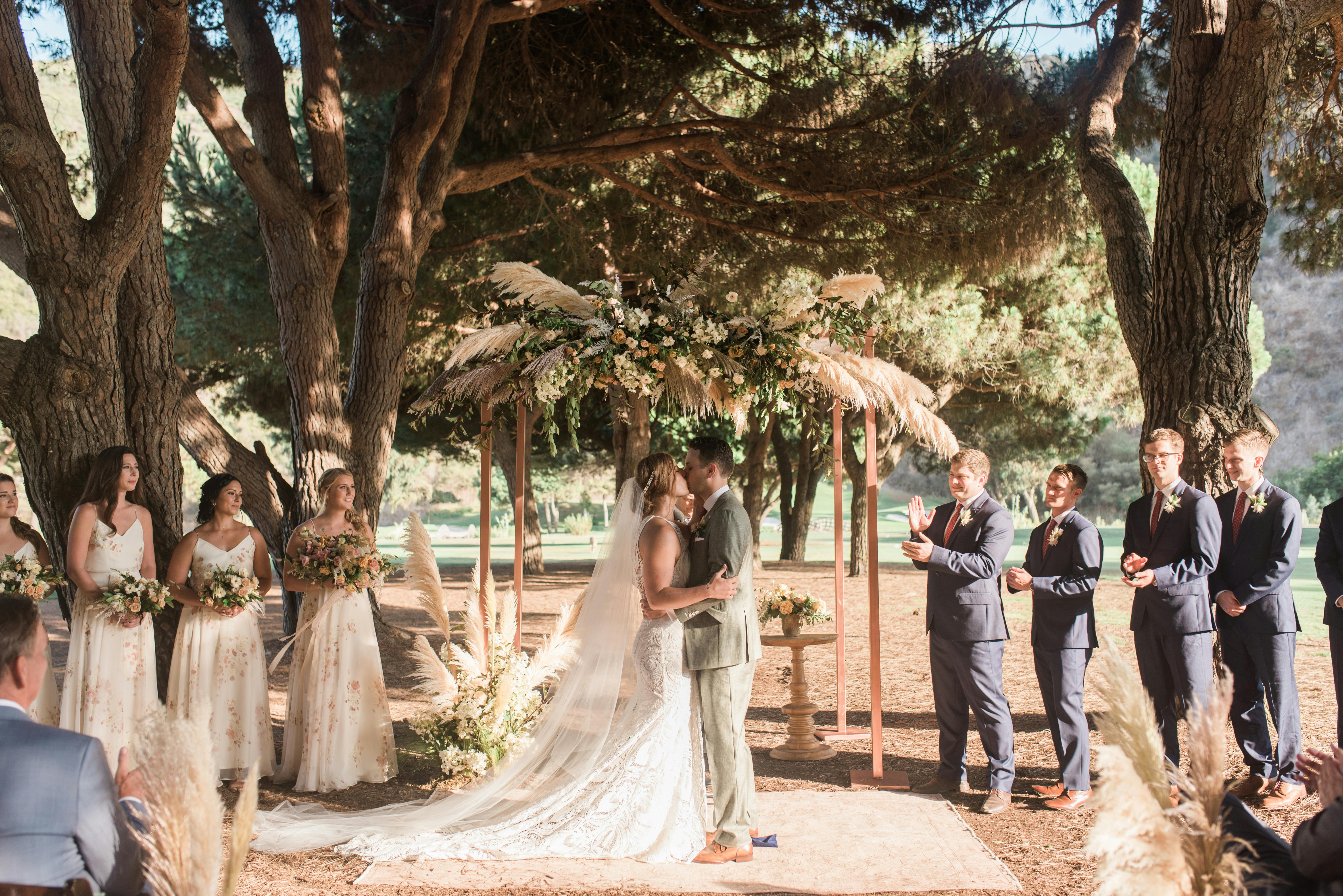 A couple at the end of the aisle with trees in the background 