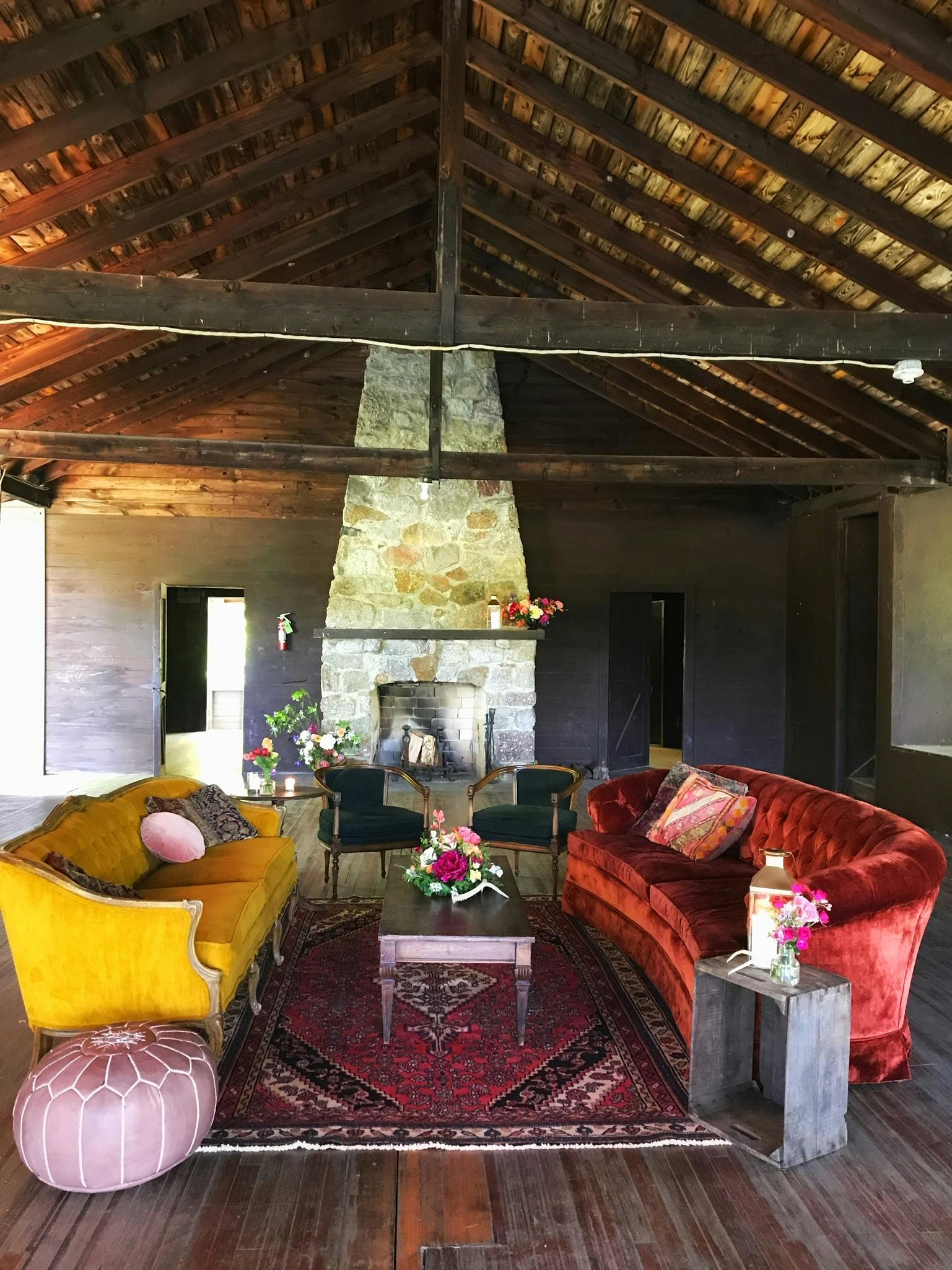 a mustard and fire red couch face each other in a vaulted room with a tall fire place 
