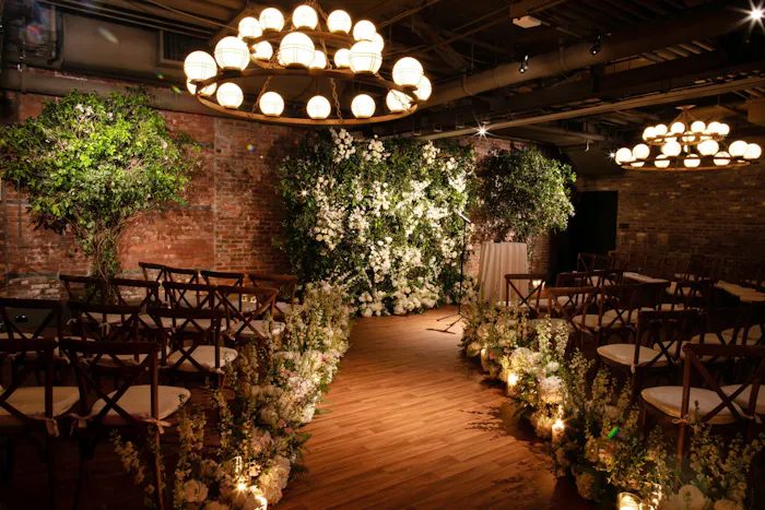 A dimly lit room with stunning chandeliers and large greenery pieces