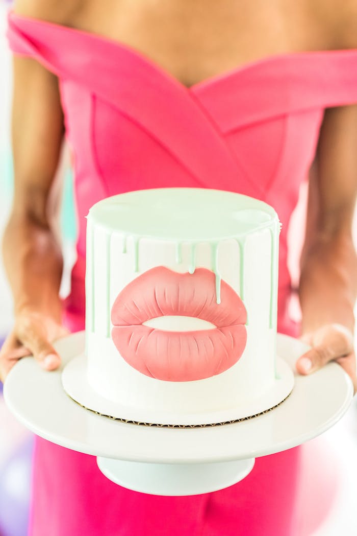 Woman in pink dress holding a Kylie Jenner themed cake | PartySlate