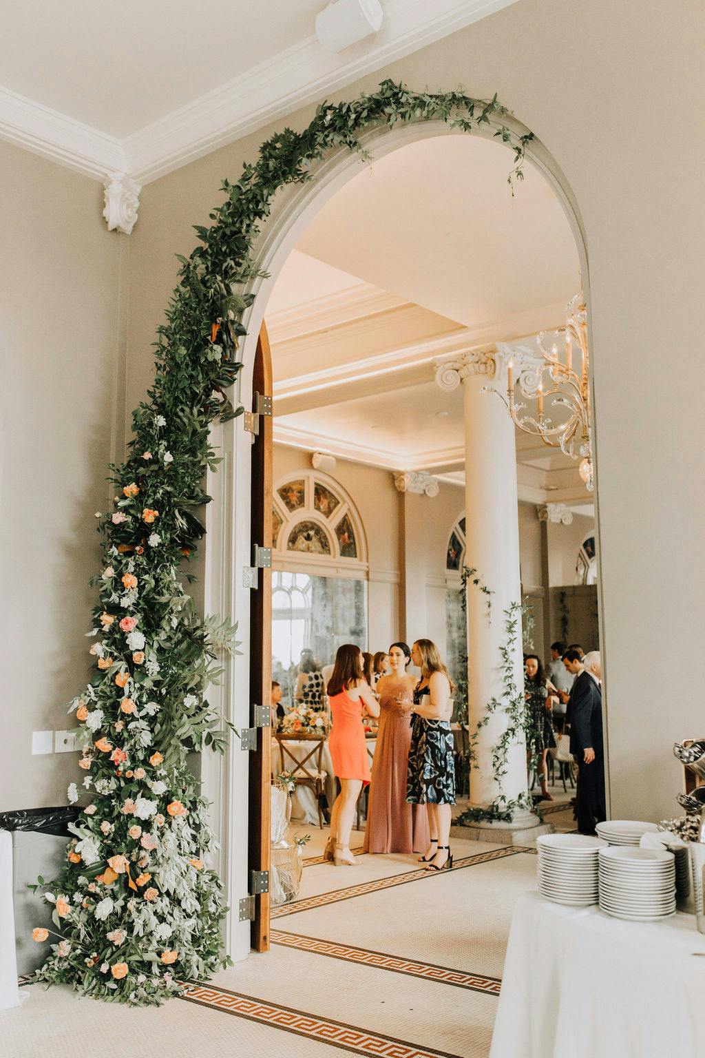 indoor archway lined with greenery and pink and white florals