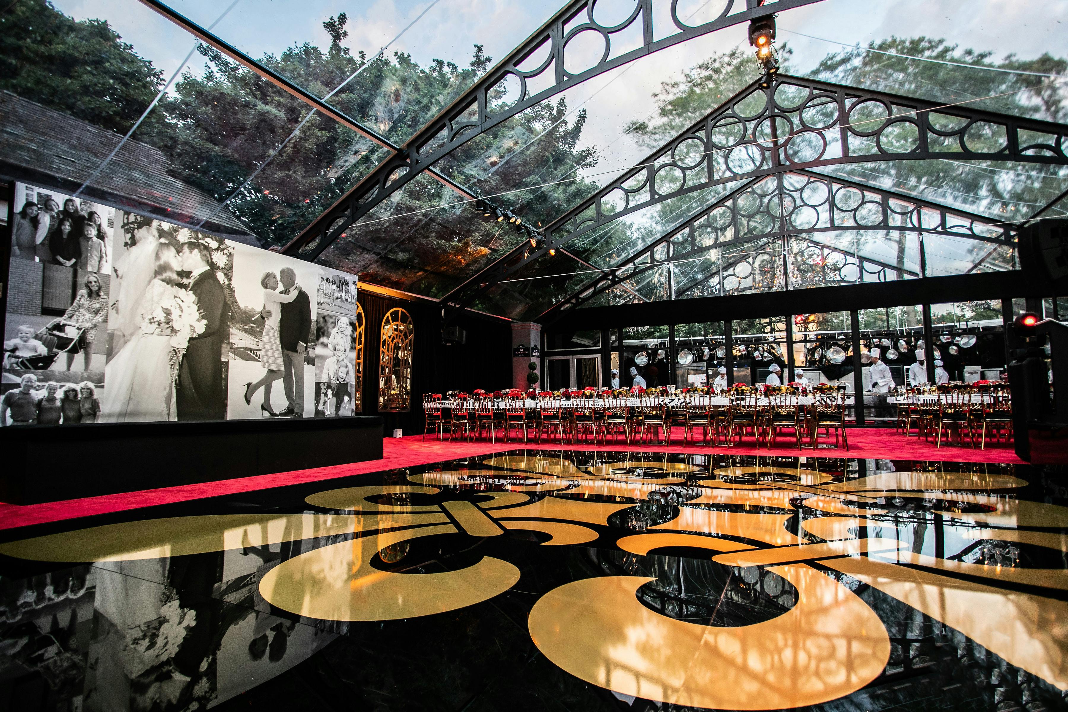 Black and gold lacquer dance floor with paned window ceilings and dining area on a red carpet at the back | PartySlate