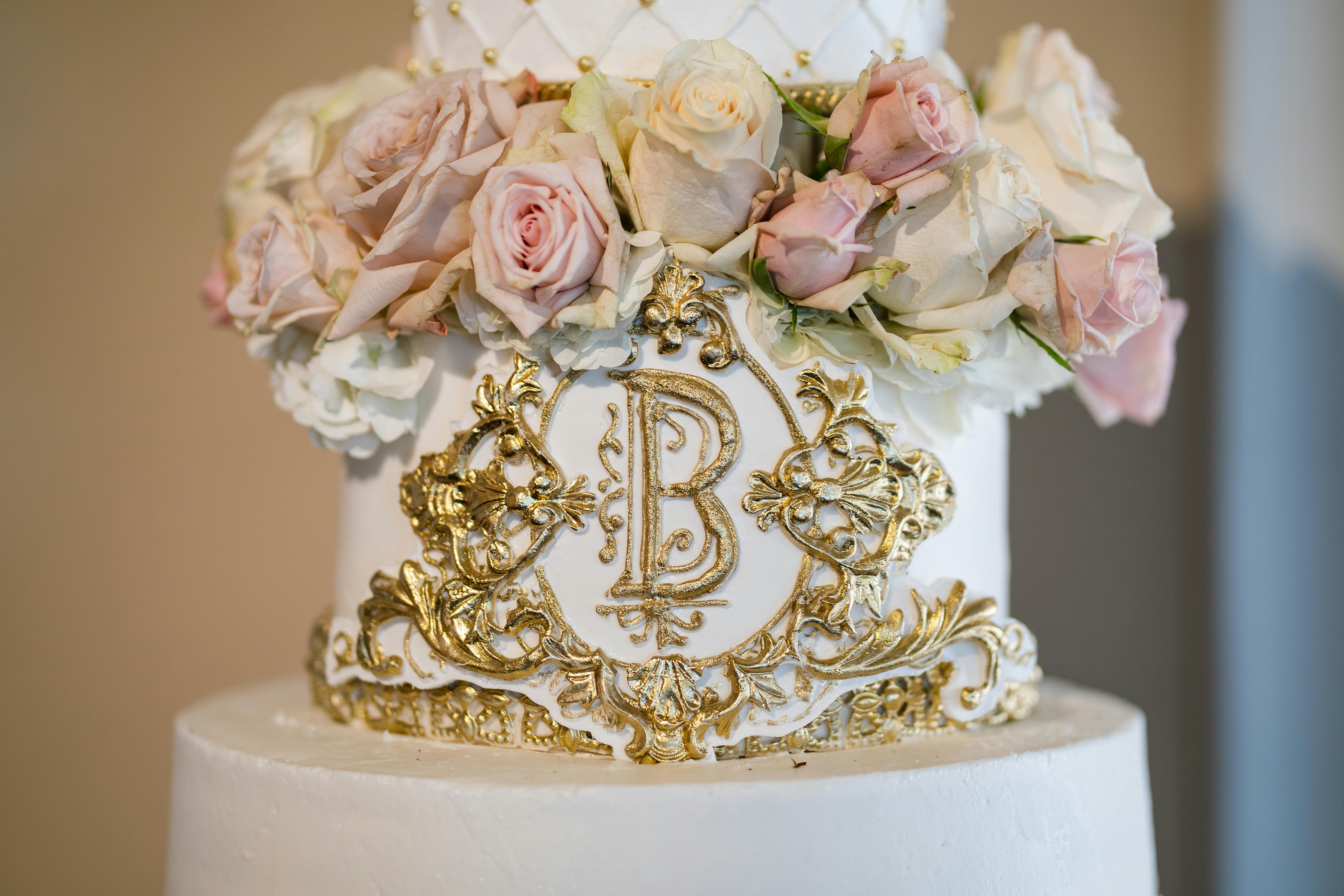 A white cake with gold carving and pink and white florals