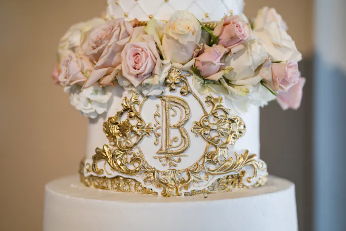 A white cake with gold carving and pink and white florals