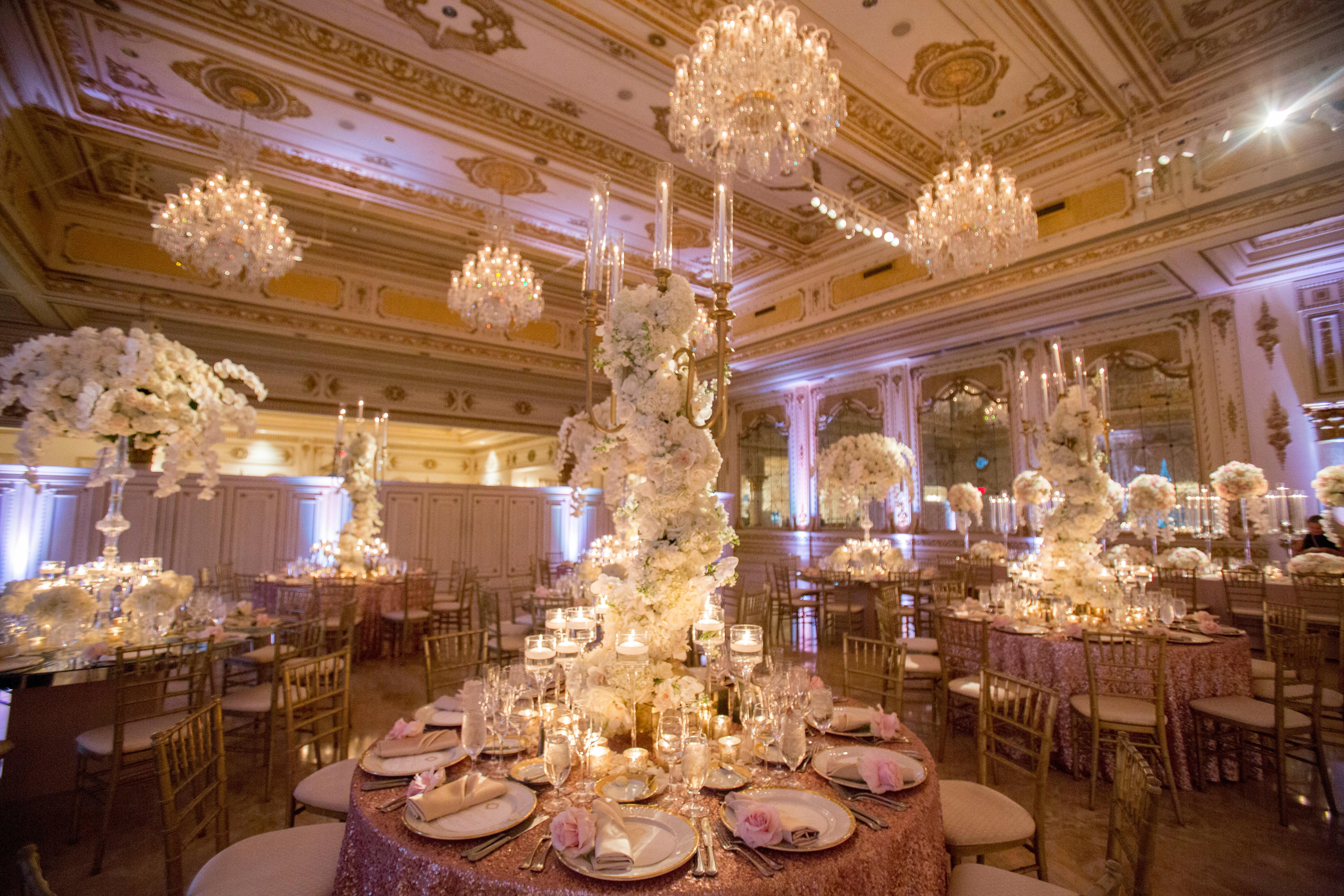 Tables with large large white bouquets in the middle that climb up to the chandeliers on the ceiling