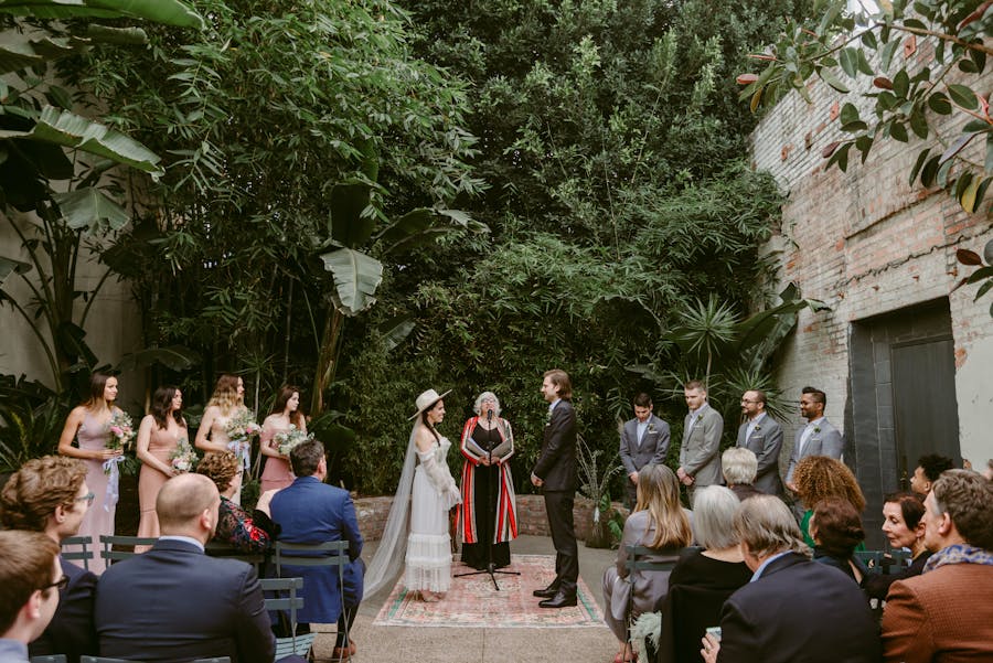 A couple holds hands at the end of the alter. Dense forest is directly behind the couple. 