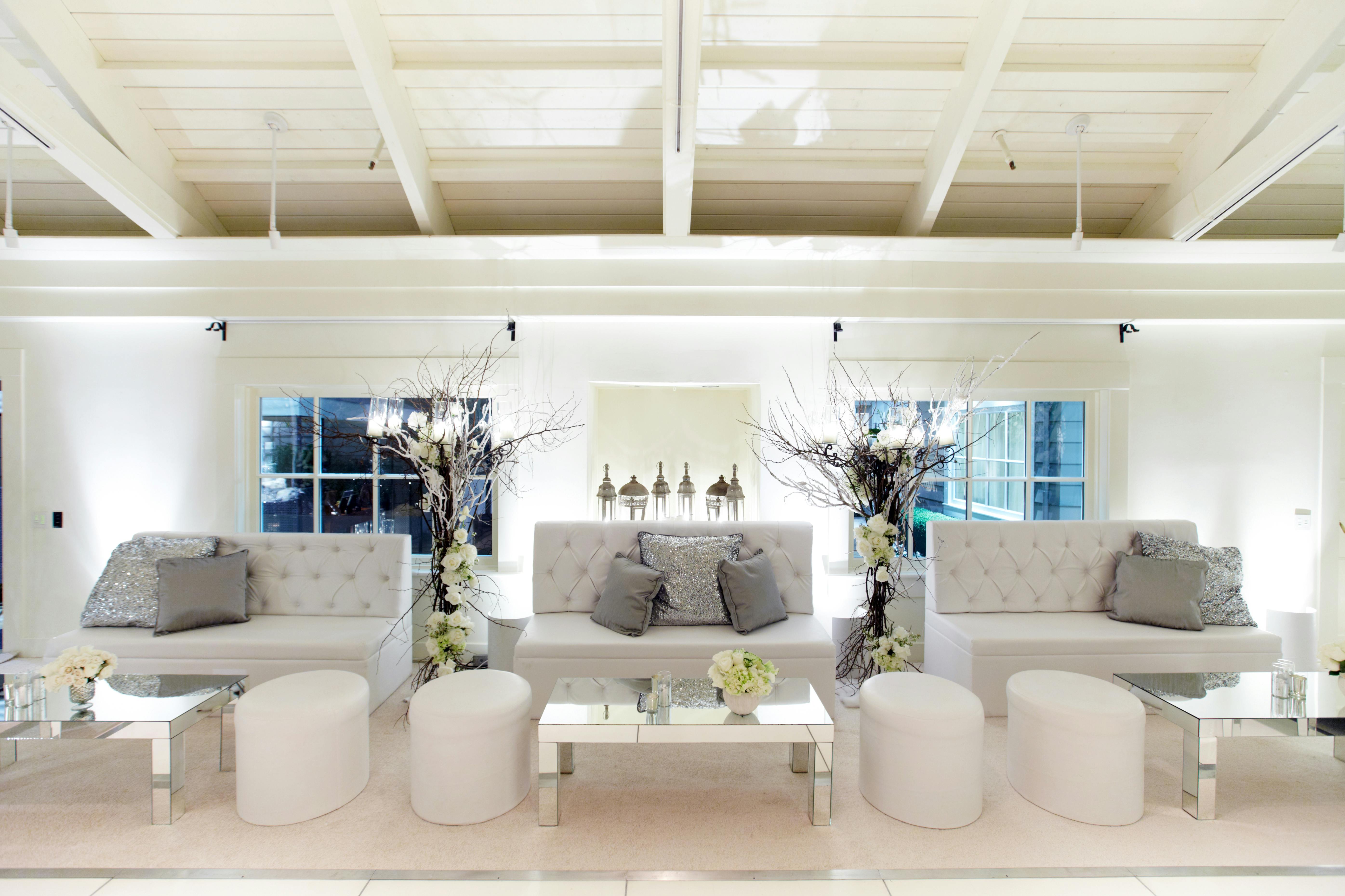 An all white color palette with three couches and four floor poufs