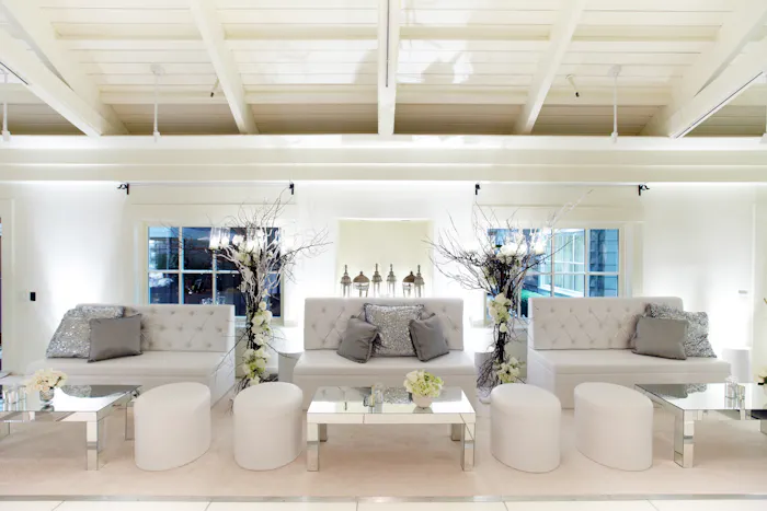 An all white color palette with three couches and four floor poufs