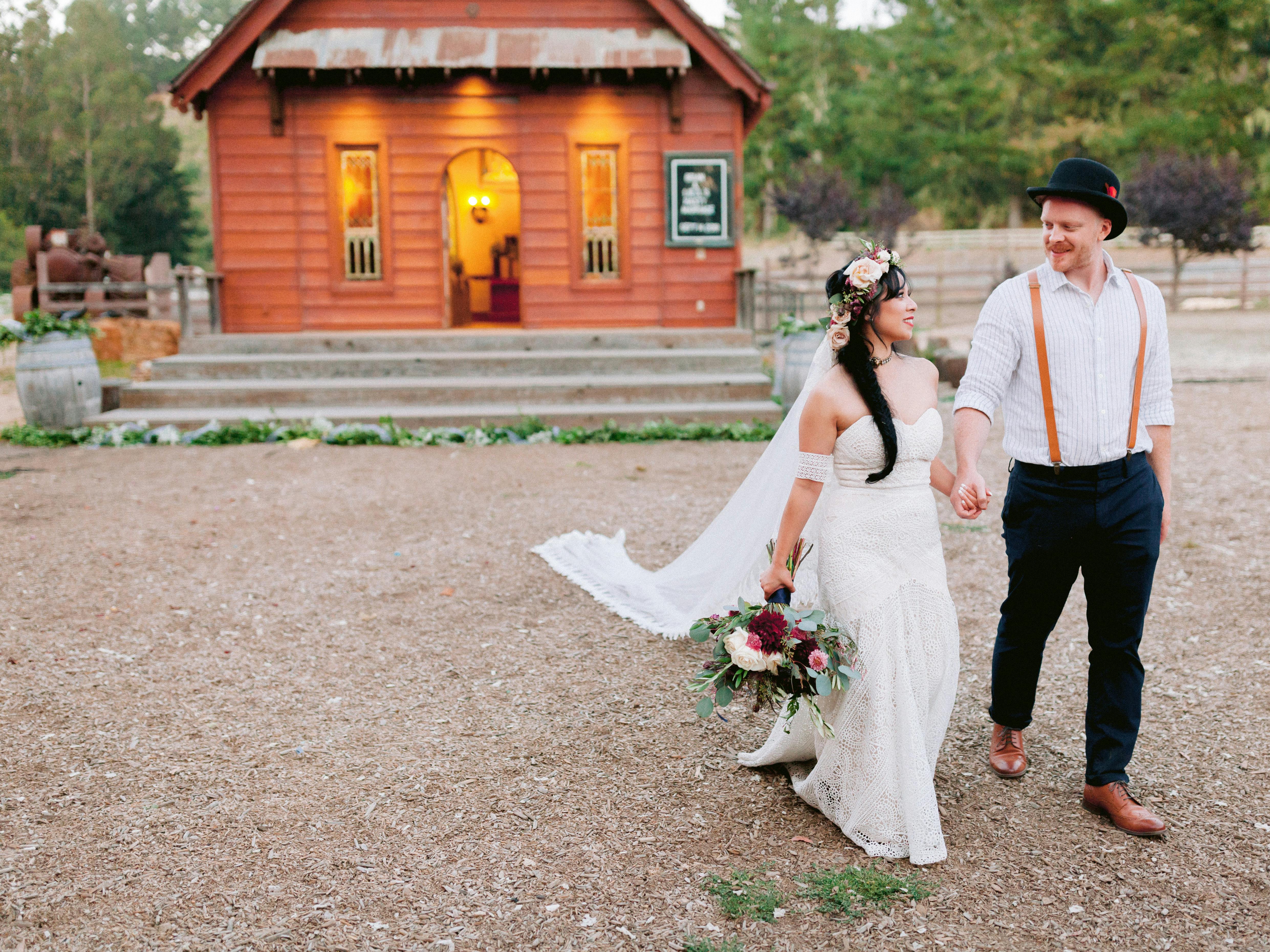 A couple walks away from a warmly lit cabin in the woods 
